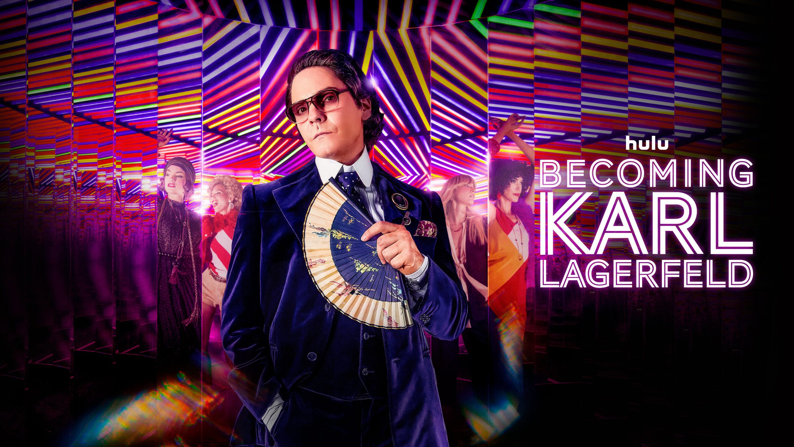 Becoming Karl Lagerfeld -- Season 1 -- In 1972, Karl Lagerfeld (Daniel Brühl) is 38 and not yet wearing his iconic hairstyle. He is a ready-to-wear designer, unknown to the general public. While he meets and falls in love with the sultry Jacques de Bascher (Théodore Pellerin), an ambitious and troubling young dandy, the most mysterious of fashion designers dares to take on his friend (and rival) Yves Saint Laurent (Arnaud Valois), a genius of haute couture backed by the redoubtable businessman Pierre Bergé (Alex Lutz).  "Becoming Karl Lagerfeld" plunges us into the heart of the 70s, in Paris, Monaco and Rome, to follow the formidable blossoming of this complex and iconic personality of Parisian couture, already driven by the ambition to become the Emperor of fashion.(Courtesy of Disney)