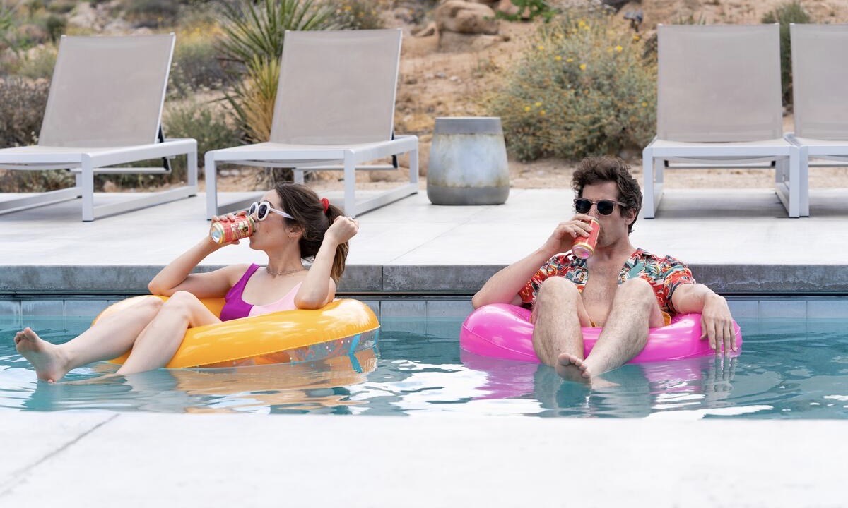 Man and woman sitting on pool floats drinking from cans