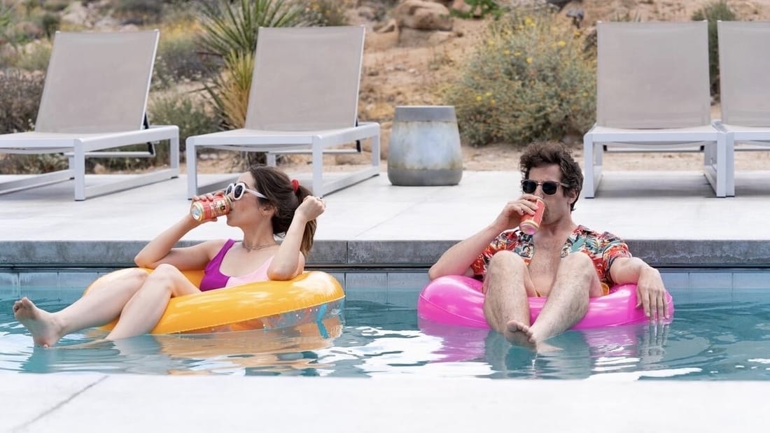 Woman and man sitting in pool floats drinking from cans