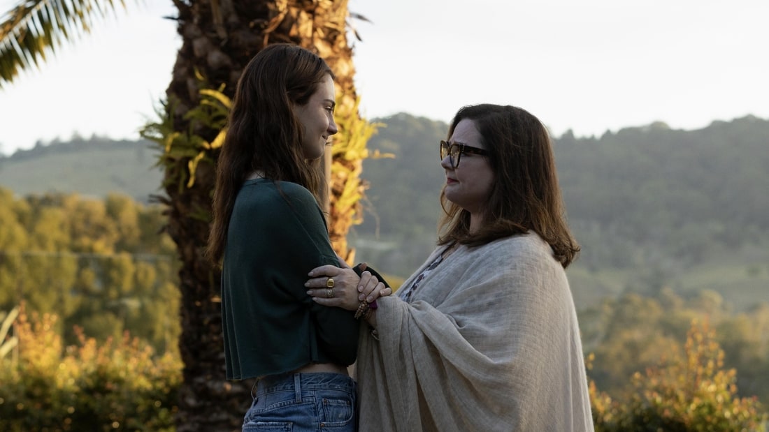 Frances (Melissa McCarthy) and Zoe (Grace Van Patten) embracing one another under a palm tree in Nine Perfect Strangers.